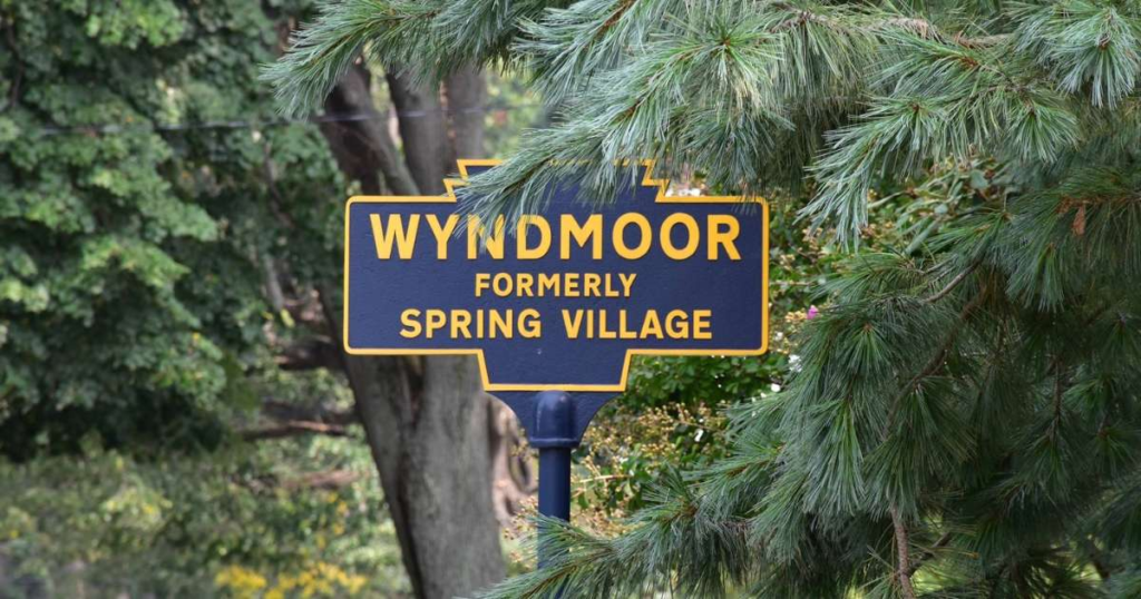 A blue and yellow historical welcome town sign for Wyndmoor